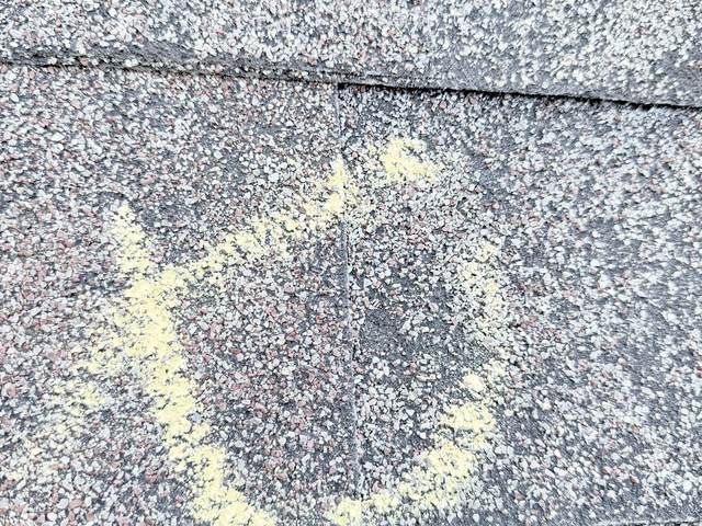Chalk circle around a hail mark on a weathered shingle