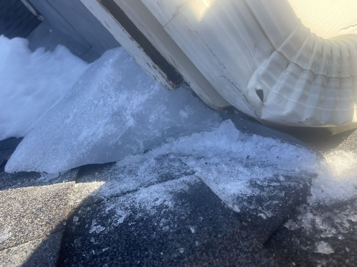 Thick ice built up on the roof at the bottom of a downspout