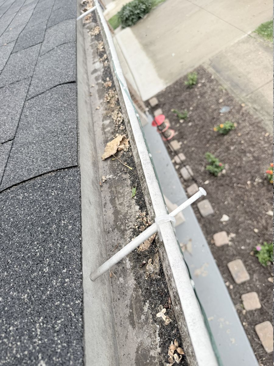 Gutter spike backed out and sticking up from a gutter full of debris